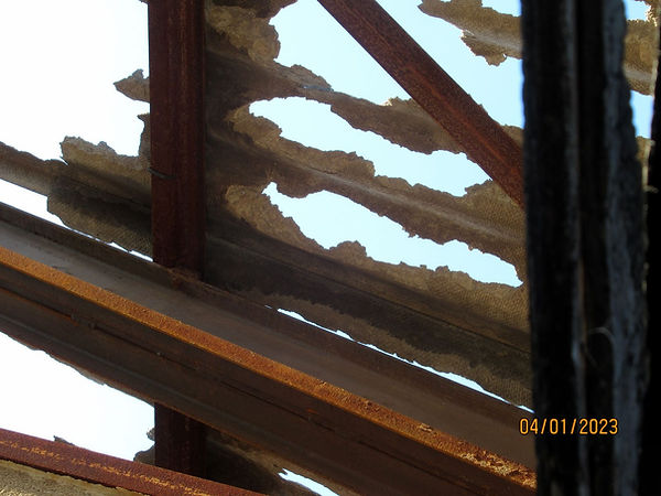 Des morceaux de plaques amiantées subsistent sur la structure métallique de la toiture.